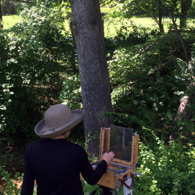 Colleen Webster from behind painting a tree near the creek at the Sanctuary.