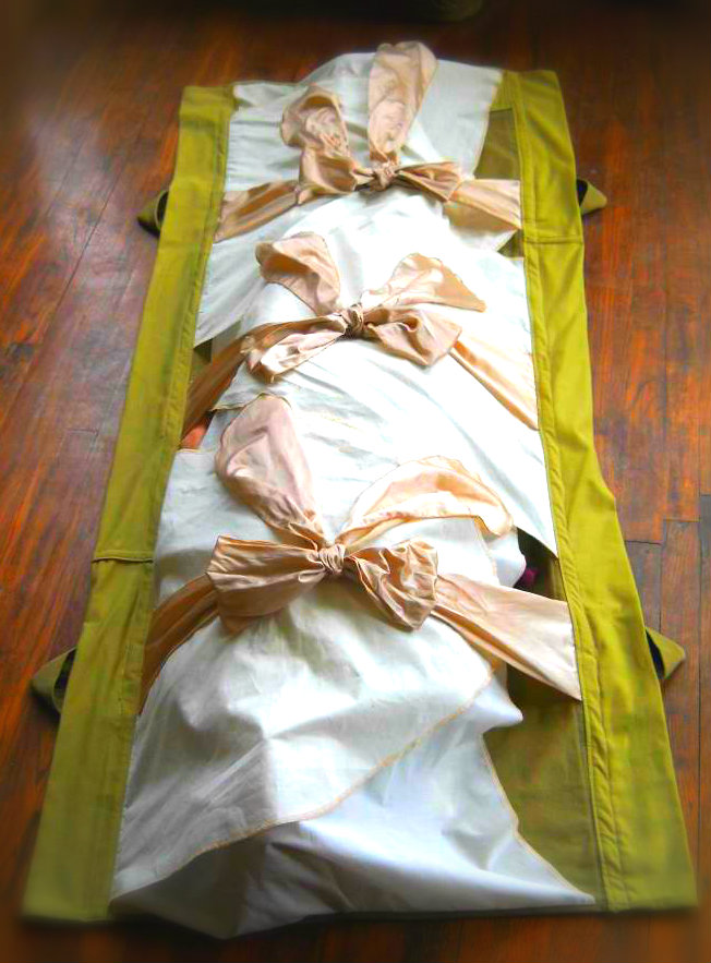 burial shroud with pink ties and a green background