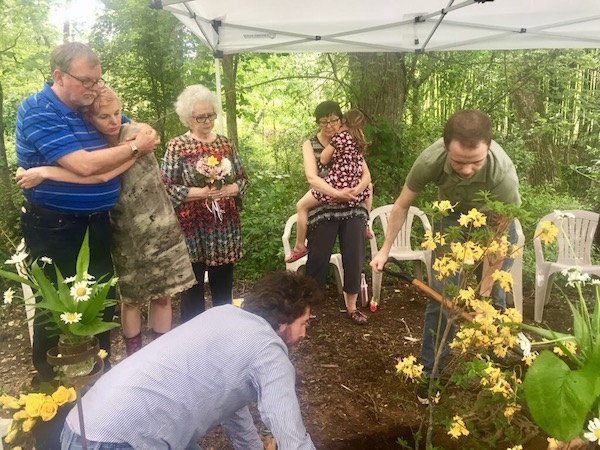 Family watches as grave is closed.