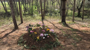 Natural burial grave covered with flowers in the woods
