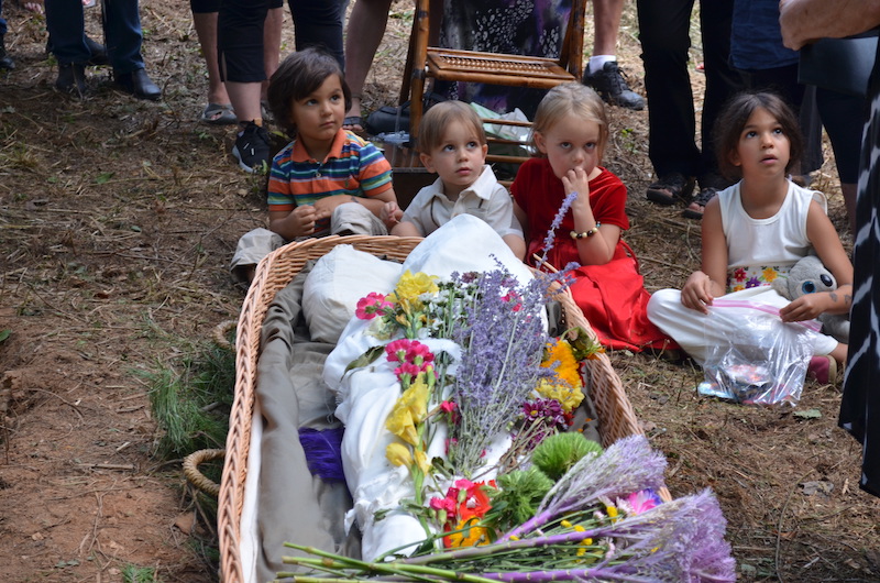 Four children sitting at the graveside near deceased Paula Brown wrapped in a shroud.
