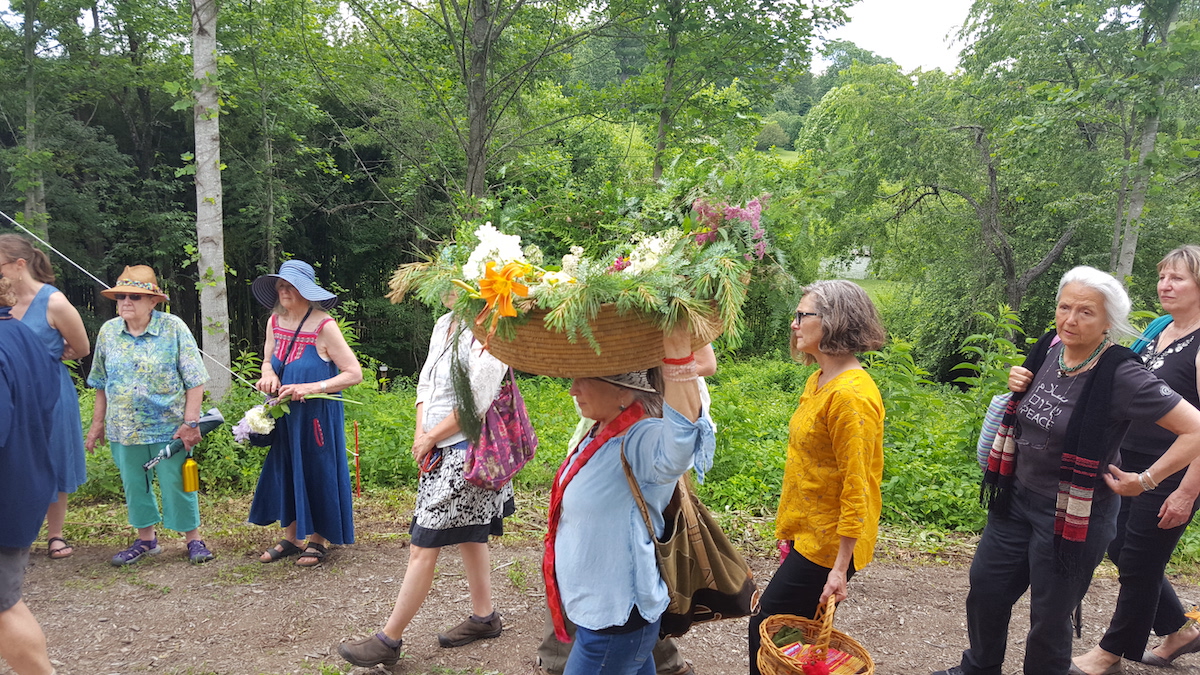 group of guests at a burial. woman in the middle carrying a basket of flowers on her head