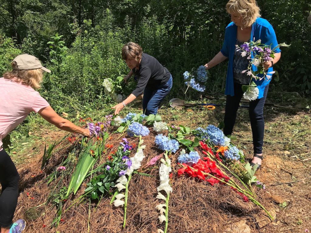 three women decorating a grave with flowers