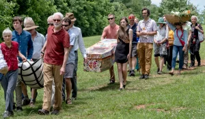 Several people carrying a decorated cardboard coffin.